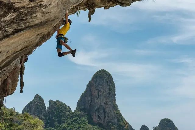 Un grimpeur suspendu à un toit calcaire au-dessus des pitons de Tonsai, Krabi