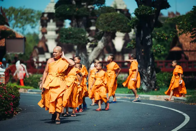 Moines bouddhistes en robe safran marchant le long d’un temple