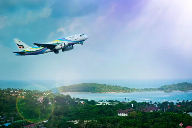 Un avion de Bangkok Airways s’élevant au-dessus d’une côte verdoyante