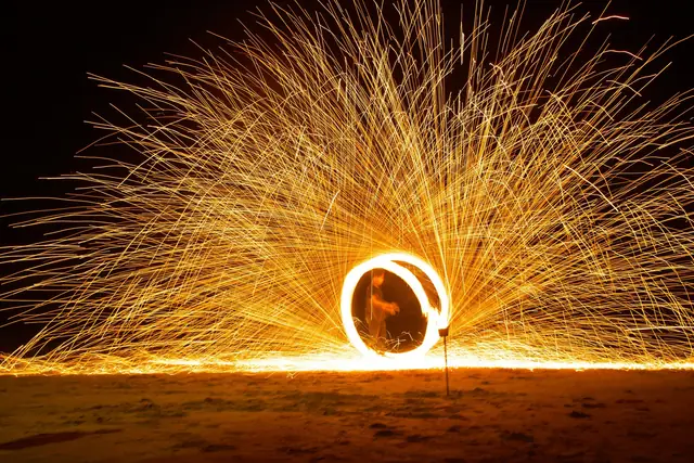 Jongleur de feu et gerbe d’étincelles sur une plage la nuit, Koh Samui