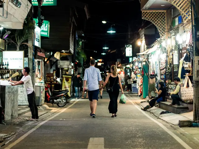 Couple marchant dans une rue de boutiques et de restaurants éclairée la nuit, Koh Samui